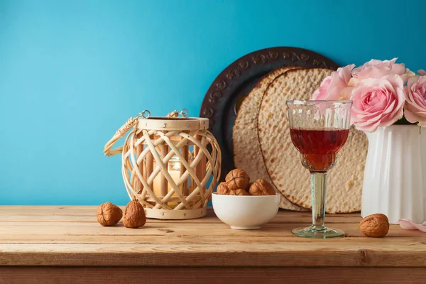 ユダヤ人の休日青い背景の上に木製のテーブルの上にワイングラス マツアと花と過越の概念 — ストック写真