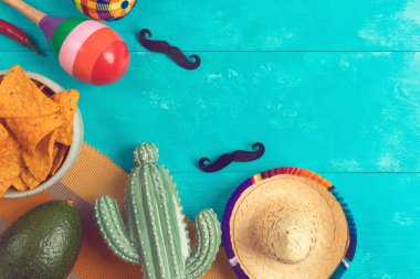 Meksika usulü cips, kaktüs, marakas, avokado ve ahşap arka planda sombrero şapkalı parti konsepti. Cinco de Mayo bayram kutlaması. Üst manzara, düz uzanma