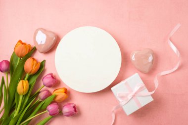 Beyaz daire, lale çiçeği, kalp şekli ve pembe arka planda hediye kutusu ile anneler günü konsepti kutlu olsun. Üst manzara, düz uzanma