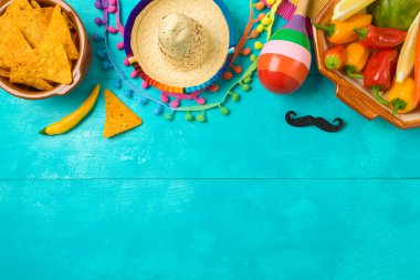 Cinco de Mayo bayram kutlaması. Mavi ahşap arka planda nacho cipsleri, biberler, marakalar ve Meksika parti dekorasyonlarıyla. Üst manzara, düz uzanma