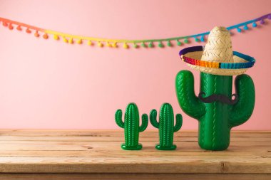 Meksika partisi konsepti. Kaktüs ve sombrero şapkalı. Ahşap masa üzerinde pembe arka plan. Cinco de Mayo bayram kutlaması