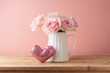 Gül buketi ve pembe arka plan üzerinde ahşap masa üzerinde kalp şeklinde Anneler Günü konsepti