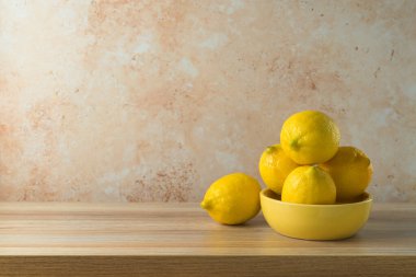 Sarı kasedeki limonlar ahşap masa üzerinde. Mutfak tasarım ve ürün gösterimi için hazırlandı