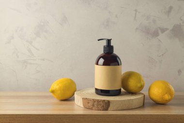 Ahşap masanın üzerinde limon özü olan şampuan ya da duş jeli şişesi. Paketleme tasarım arkaplanını düzenle