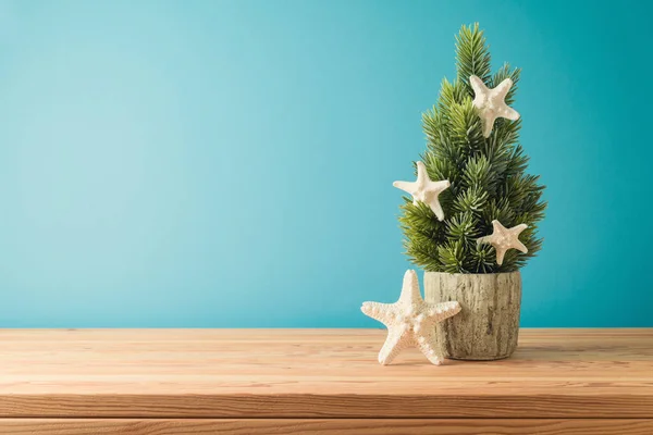 七月的圣诞节概念 圣诞树和海星放在蓝色背景的木制桌子上 — 图库照片