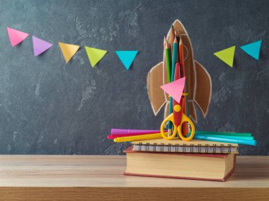 Okul konseptine geri dönelim. Roket, kalem ve tahta masa üzerine kitap.