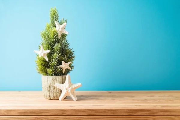 青い背景の上に木のテーブルの装飾が付いている創造的なクリスマス ツリー — ストック写真