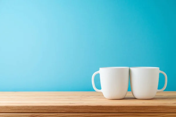 Λευκά Φλιτζάνια Καφέ Ξύλινο Τραπέζι Πάνω Από Μπλε Φόντο Μακέτα — Φωτογραφία Αρχείου