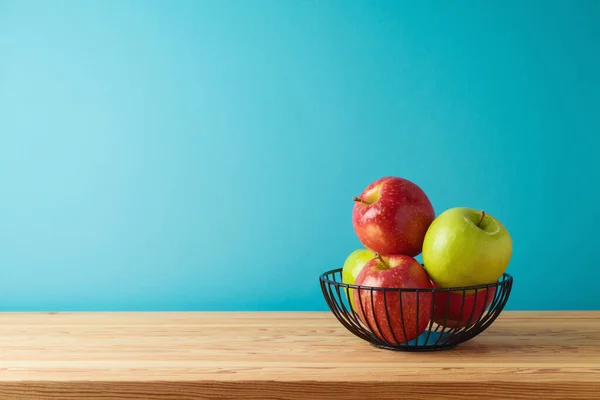 红色和绿色的苹果放在木制桌子上的金属篮子里 厨房的背景 — 图库照片
