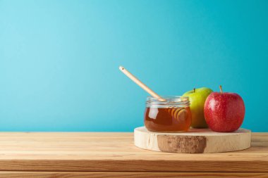 Bal kavanozu ve elmalar ahşap masada mavi arka planda. Yahudi bayramı Rosh Hashanah kavramı
