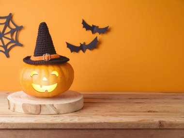 Cadılar Bayramı balkabağı süslemesi ahşap masa üzerinde turuncu duvar arka planında