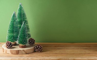 Yeşil arka planda çam ağacı süslemesi olan ahşap masa. Noel ve kış tatilleri tasarım ve ürün gösterimi için hazırlanır.