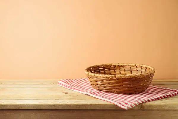 Empty basket on  table with red checked tablecloth over modern beige background.  Kitchen or bakery mock up for design and product display