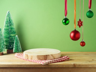 Ahşap masa örtülü boş kütük podyumu yeşil duvarın üzerinde ve çam ağacı süsleme arka planında. Tasarım ve ürün gösterimi için Noel modeli.