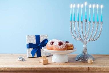 Menorah, geleneksel çörekler ve tahta masadaki hediye kutusuyla Yahudi bayramı Hanukkah konsepti..