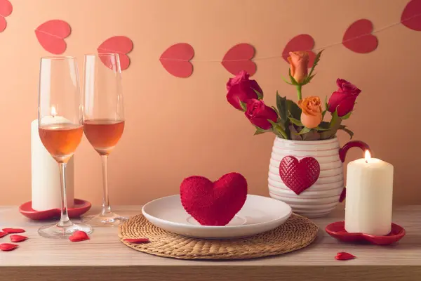 Valentine\'s day romantic dinner concept. Wooden table with plate, heart shape, wine, flowers and candles over peach color background