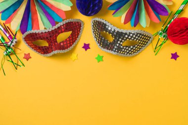Altın karnaval maskeleri ve sarı arka planda parti süslemeleri olan karnaval ya da Mardi Gras konsepti. Üst manzara, düz uzanma
