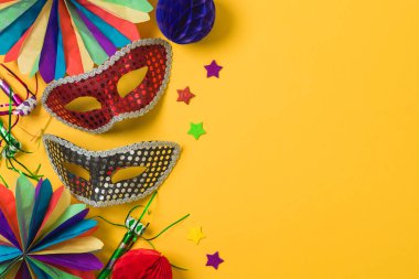 Altın karnaval maskeleri ve sarı arka planda parti süslemeleri olan karnaval ya da Mardi Gras konsepti. Üst manzara, düz uzanma