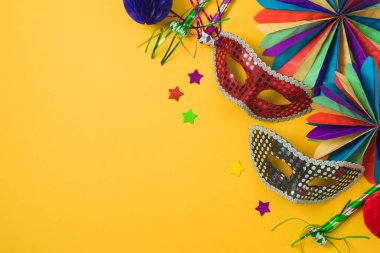 Altın karnaval maskeleri ve sarı arka planda parti süslemeleri olan karnaval ya da Mardi Gras konsepti. Üst manzara, düz uzanma