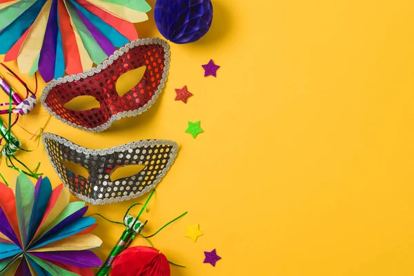 Altın karnaval maskeleri ve sarı arka planda parti süslemeleri olan karnaval ya da Mardi Gras konsepti. Üst manzara, düz uzanma