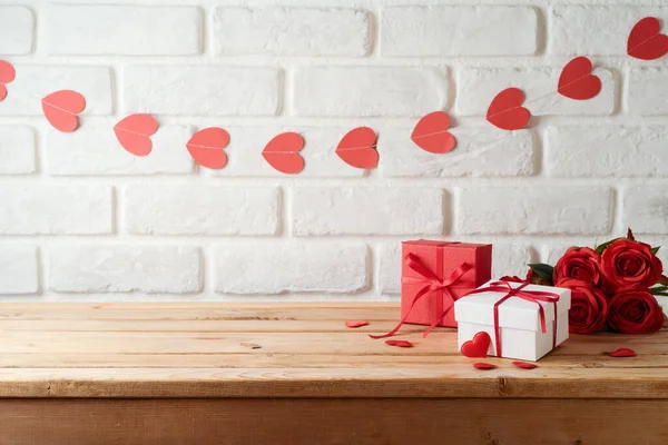 Valentinstag Hintergrund Mit Leeren Holztisch Geschenkbox Und Herzformen Über Ziegelwand lizenzfreie Stockbilder