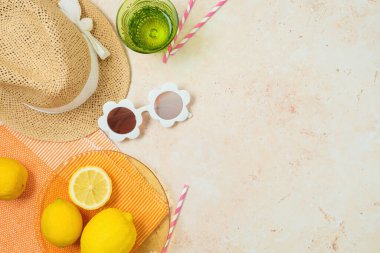 Hasır şapkalı, limonlu ve modern arka planda güneş gözlüklü yaz pikniği konsepti. Üst manzara, düz uzanma