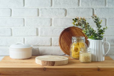 Mutfak masasında boş ahşap kütük, yemek kavanozları ve bitkiler beyaz tuğla duvar arkasında. Mutfak tasarım ve ürün gösterimi için hazırlandı.