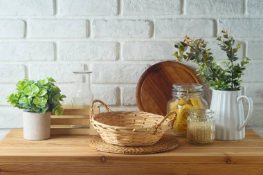 Mutfak masasındaki boş sepetin üzerinde yemek kavanozları ve bitkiler beyaz tuğla duvar altyapısı var. Mutfak tasarım ve ürün gösterimi için hazırlandı.