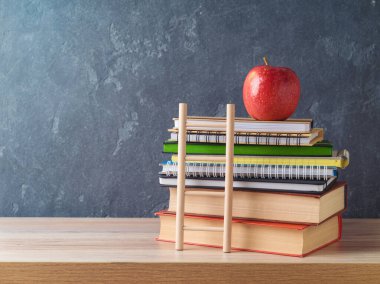 Kitap, defter ve elma tahtası üzerinde tahta masa ve arkaplanla okula geri dön.
