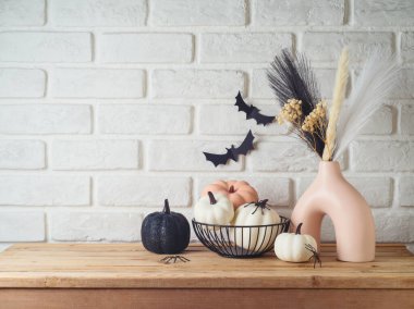 Modern vazo ve dekorasyonlu cadılar bayramı arkaplanı tuğla duvarın üzerindeki ahşap masada. Ürün görüntüleme için boş alan