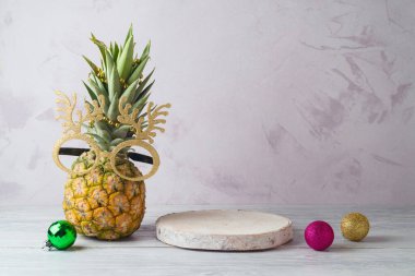 Ananaslı Noel tatili konsepti, komik parti bardakları ve ahşap masa üzerindeki boş ahşap kütük podyumu.