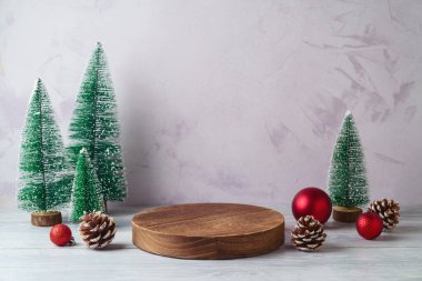 Boş kütük podyumu ve çam ağacı süslemesi beyaz ahşap masa üzerinde parlak duvar zemininde. Tasarım ve ürün gösterimi için Noel modeli.