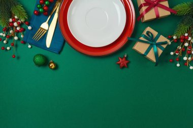 Tabaklı Noel masası süsü, hediye kutusu ve yeşil arka planda süsler. Tatil kartı, davetiye ve tasarım için zarif bir şablon