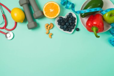 Sağlıklı yaşam tarzı ve dengeli yemek geçmişi sebze, meyve, yabanmersini, tıbbi steteskop ve dambıllarla