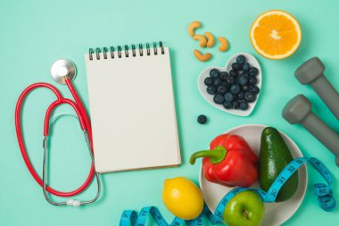 Sebze, meyve, tıbbi steteskop, dambıl ve defterle sağlıklı yaşam tarzı ve dengeli diyet kavramı