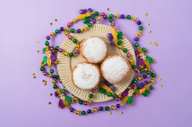 Mardi gras karnaval çörekleri, boncuklar ve mor bir arka plan.