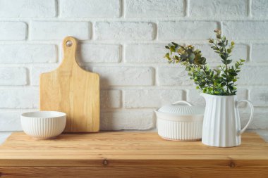 Mutfak aletleriyle mutfak masası ve beyaz tuğlalı arka planda bitki örtüsü. Mutfak tasarım ve ürün gösterimi için hazırlandı