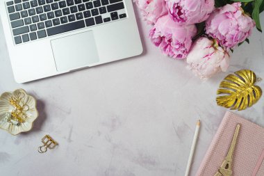 Kadınsı ofis masası. Dizüstü bilgisayarı ve şakayık çiçekleri olan blog konsepti. Üst manzara, düz uzanma