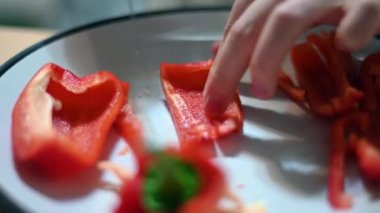 A perfectly sliced red pepper is just a few cuts away with this close up selective focus shot of a sharp knife at work.