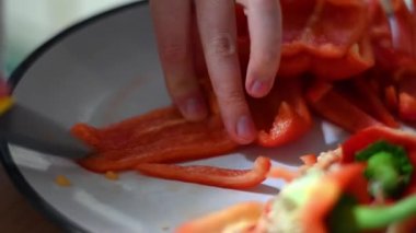 A close-up of a woman's hands expertly chopping a red pepper for a healthy meal.