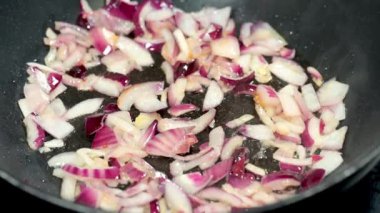 Sıcak bir tavada kırmızı soğanın cızırdadığı bu yakın çekim görüntüsü yemek pişirme sürecinin özünü yakalar, sıcaktan buhara ve lezzetli aromaya kadar..
