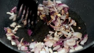 Hareketin ve doğranmış kırmızı soğanın sıcak tavada bir balık dilimi tarafından karıştırılmasının yavaş çekim videosu..