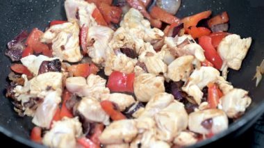 Çiğ tavuk ve kırmızı biber kızarmış soğanla tavada cızırdıyor.