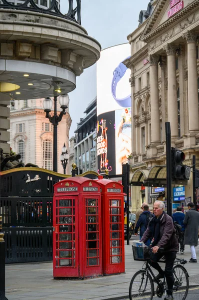 2022年11月13日 在伦敦最繁忙的交叉口之一 充满活力的皮卡迪利广场 一个男人骑自行车穿过传统的红色电话亭 — 图库照片