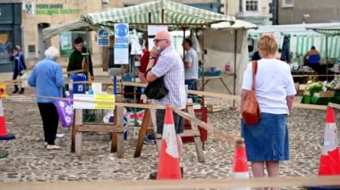 Richmond, Kuzey Yorkshire, İngiltere - 1 Ağustos 2020: Yüz maskeli yaşlı yetişkinler, açık hava pazarının girişinde el dezenfektanı için kuyruğa girerler, alışveriş yaparken güvenliklerini sağlarlar.