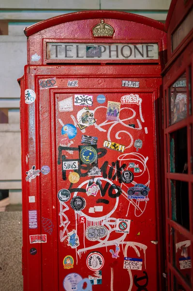 LONDON - 21 Nisan 2023: Londra 'nın şehir sanat sahnesinin ikonik sembollerini gece vakti graffiti kaplı geleneksel İngiliz telefon kulübesini ziyaret ederek keşfedin.