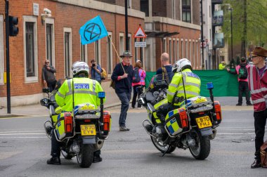 22 Nisan 2023: Motosikletli Metropolitan polis memurları Londra 'daki Soykırım İsyanı' nda halkın güvenliğini sağlarken bir protestocu bayrak sallıyor..