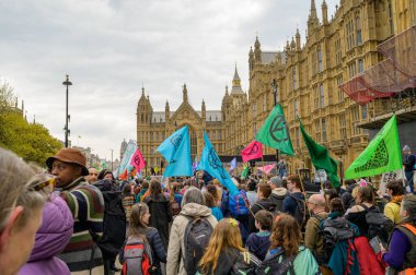 LONDON - 22 Nisan 2023: XR protestocularının bayrakları dalgalanan, Parlamento Meydanı 'na yürüyen, sürdürülebilir bir gelecek için güçlü bir mesaj taşıyan çarpıcı görüntülerini tecrübe edin.