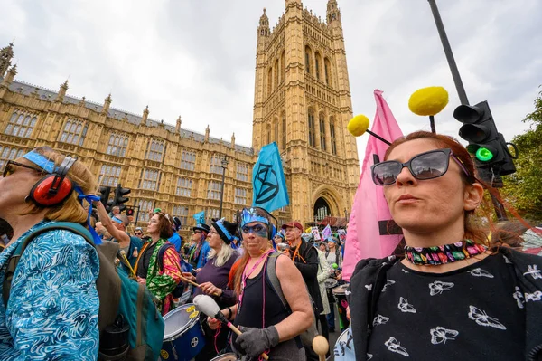 stock image LONDON - April 22, 2023: Join the dynamic activism in motion as Extinction Rebellion protesters march past the Houses of Parliament, their voices raised for environmental justice and climate action.