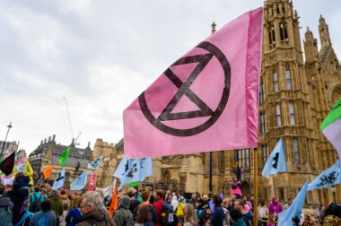 LONDON - 22 Nisan 2023: Güçlü görüntüye bakın: XR, parlamento yakınlarındaki XR yürüyüşünde protestocuların üzerinde dalgalanan XR bayrağı, değişim için ortak mesajlarını sembolize ediyor.